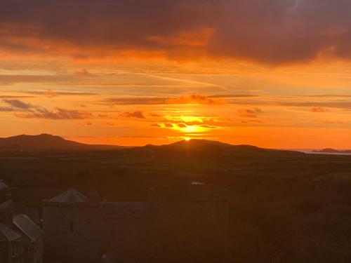 a sunset with the sun setting over a mountain at St Davids Gin & Kitchen - The Cathedral Villas in St. Davids