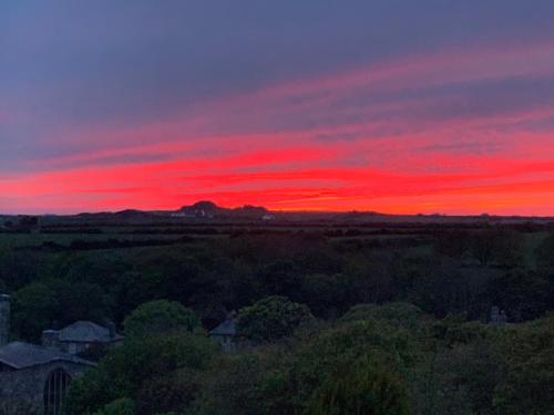 a sunset over a field with a red sky at St Davids Gin & Kitchen - The Cathedral Villas in St. Davids