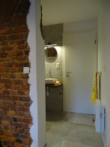 a brick wall next to a bathroom with a sink at La Maison de Julienne - Ligneuville in Malmedy