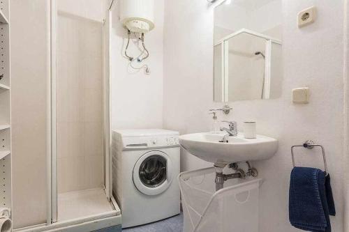 a white bathroom with a washing machine and a sink at Piso confortable y céntrico in Madrid