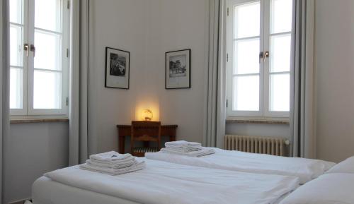 two white beds in a room with windows at Haus Bischofsstab - Ferienwohnung am Meer in Heiligendamm