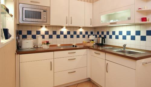 a kitchen with white cabinets and a sink and a microwave at Ferienwohnung Antonia in Kühlungsborn