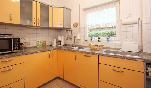 a kitchen with yellow cabinets and a sink and a window at Ferienwohnung Muschelsucher in Kühlungsborn