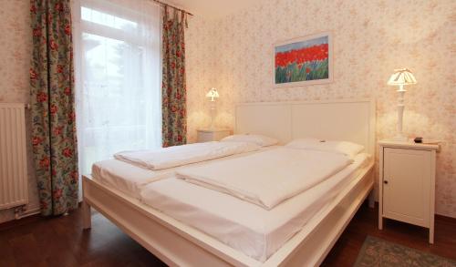 a bedroom with a large white bed with a window at Ferienwohnung Muschelsucher in Kühlungsborn