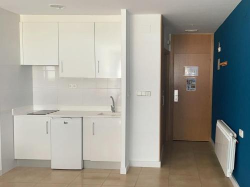 a kitchen with white cabinets and a blue wall at Estación de Montaña Manzaneda in Puebla de Trives