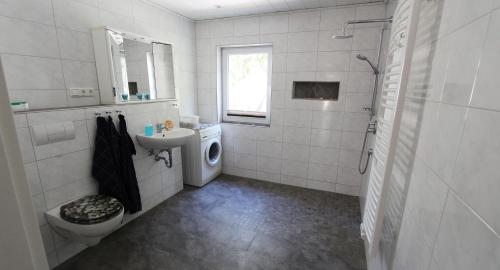 ein weißes Badezimmer mit einem Waschbecken und einer Waschmaschine in der Unterkunft Ferienwohnung Iris in Kühlungsborn