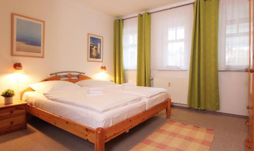 a bedroom with a large bed and two windows at Ferienwohnung Parkblick Nr. 25 in Kühlungsborn