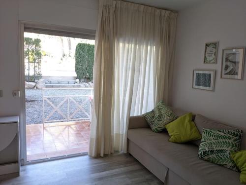 ein Wohnzimmer mit einem Sofa und einer Glasschiebetür in der Unterkunft Apartamento Cala del Pi in Platja  d'Aro