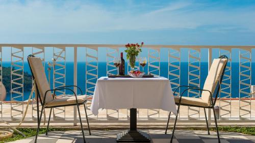 een tafel en stoelen op een balkon met uitzicht op de oceaan bij Apartments and Room Lora in Dubrovnik