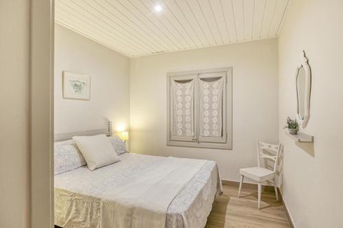 een witte slaapkamer met een bed en een stoel bij Apartamento Bajo 2 in Begur