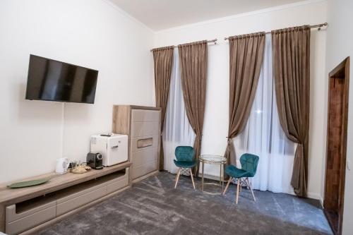 um quarto com duas cadeiras e uma televisão e cortinas em The Nest Baia Mare em Baia Mare