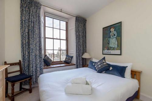 1 dormitorio con cama blanca y ventana en Stunning Panoramic Views: Heart of the Royal Mile, en Edimburgo