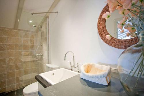 a bathroom with a sink and a vase with a mirror at The Studio Cottage, with, Sea views, Garden, Amazing Location by beach in Sennen