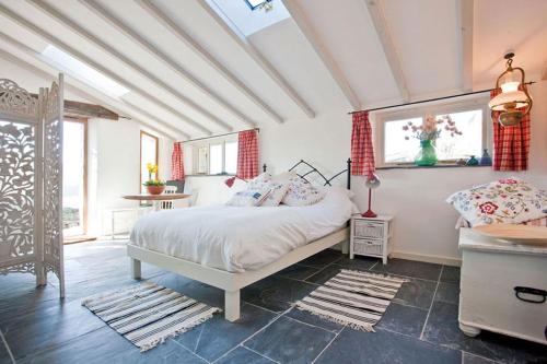 a bedroom with a white bed and a window at The Studio Cottage, with, Sea views, Garden, Amazing Location by beach in Sennen