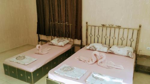 two beds with pink sheets with dolls on them at Dracena Guesthouse in Ravda