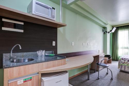 cocina con fregadero y microondas en Eko Residence Hotel - a 200m dos Hospitais da Santa Casa, en Porto Alegre