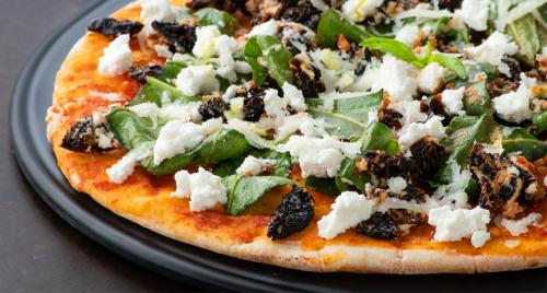a pizza with cheese and greens on a plate at Melange Astris in Bengaluru