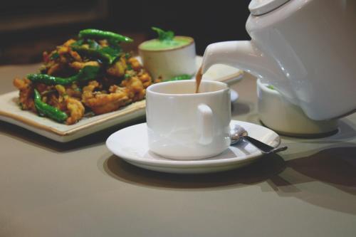 a white cup of coffee and a plate of food at Melange Astris in Bengaluru
