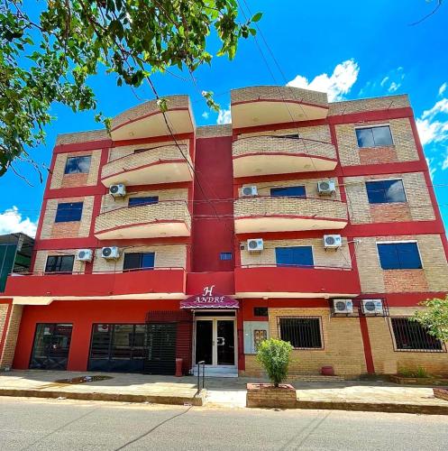 un edificio rojo en una calle con un árbol en Hotel André, en San Lorenzo