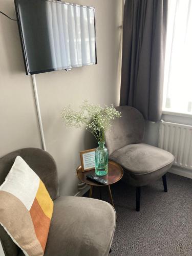 a living room with two chairs and a vase of flowers on a table at Bed and Breakfast Kik en Bun in Katwijk aan Zee