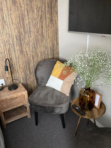 a living room with a chair and a vase with flowers at Bed and Breakfast Kik en Bun in Katwijk aan Zee