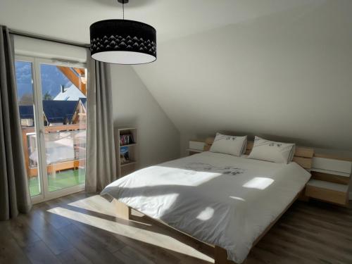 une chambre avec un lit et une grande fenêtre dans l'établissement Appartement duplex de standing au cœur des Pyrénées, à Luchon
