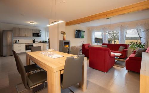 cocina y sala de estar con mesa de madera y sillas rojas en Ferienhaus Annemiete, en Putbus
