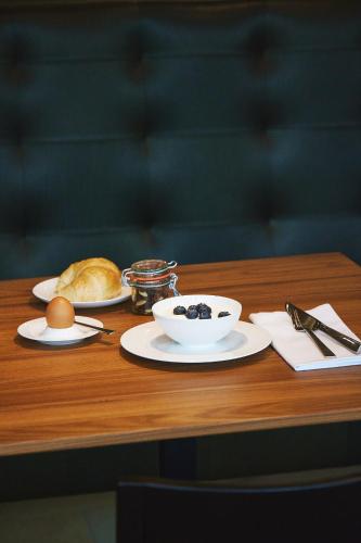 a table with plates of food and a croissant and a bowl of fruit at Hotel am See in Hard