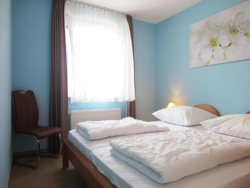 1 Schlafzimmer mit 2 Betten, einem Fenster und einem Stuhl in der Unterkunft Ferienwohnung Hanna in Kühlungsborn