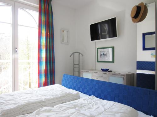 a bedroom with a bed and a tv on the wall at Ferienwohnung Waldblick Nr. 17 in Kühlungsborn