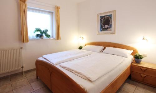 a bedroom with a bed with white sheets and a window at Ferienwohnung Seitz in Kühlungsborn