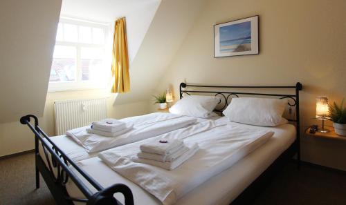 um quarto com uma cama com lençóis brancos e toalhas em Ferienwohnung Birgit em Kühlungsborn