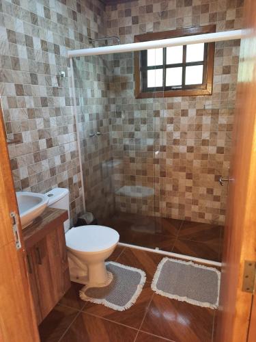 a bathroom with a toilet and a glass shower at Encanto das Rosas in Santo Antônio do Pinhal
