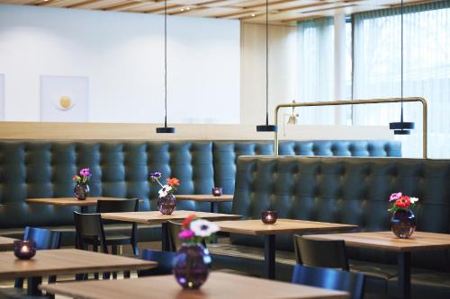 a dining room with tables and chairs with flowers in vases at Hotel am See in Hard