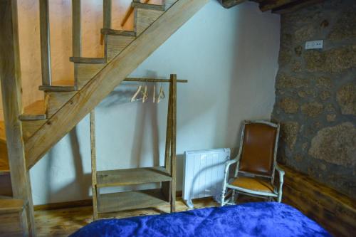 a bedroom with a bed and a staircase and a chair at Casa do Ti João in Sabugueiro
