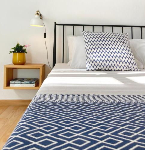 a bed with a blue and white comforter and a lamp at Asterias in Panteli