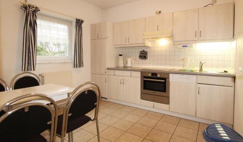 a kitchen with white cabinets and a table with chairs at Ferienwohnung Warnke in Kühlungsborn