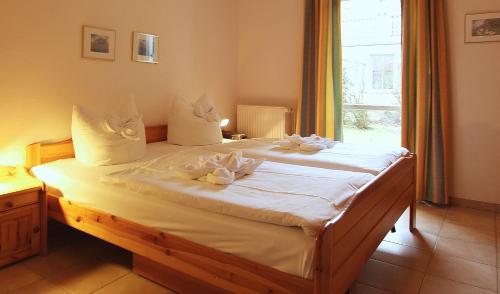 Schlafzimmer mit einem Bett mit weißer Bettwäsche und einem Fenster in der Unterkunft Ferienwohnung Warnke in Kühlungsborn