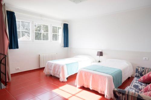 1 dormitorio con 2 camas y sofá en Orquideas, en Cala Galdana