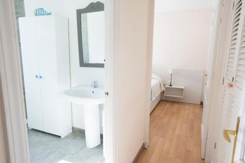 a white bathroom with a sink and a mirror at Orquideas in Cala Galdana