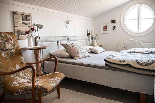 ein Schlafzimmer mit einem Bett, einem Stuhl und einem Fenster in der Unterkunft Lugnet i Oslättfors in Gävle