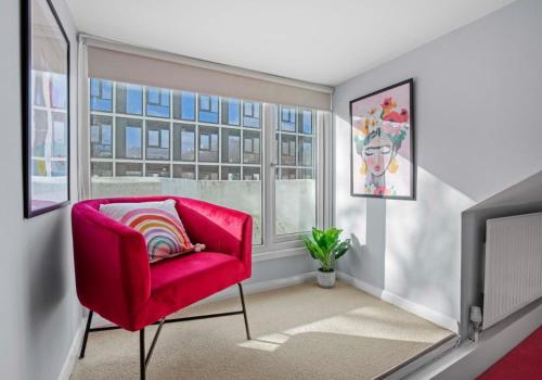 a red chair in a living room with a window at The Townhouse By My Getaways Free Parking in Brighton & Hove