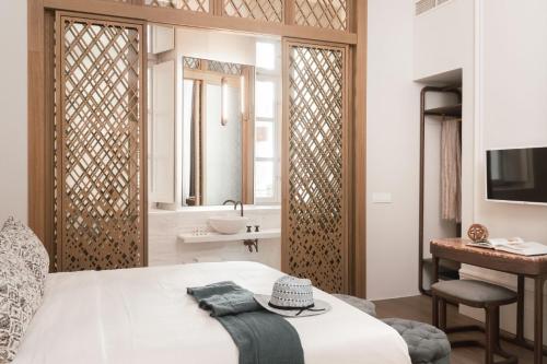 a bedroom with a bed and a bathroom with a sink at Castro Hotel Syros in Ermoupoli