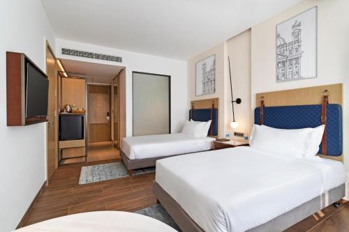 Habitación de hotel con 2 camas y TV en The Crescent en Panaji