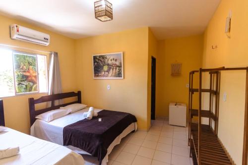 deux lits dans une chambre aux murs jaunes dans l'établissement Pousada Aruna Kite, à Barra Grande