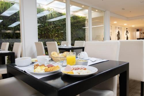 a breakfast table with breakfast foods and orange juice at Samba Bossa Nova Ipanema in Rio de Janeiro