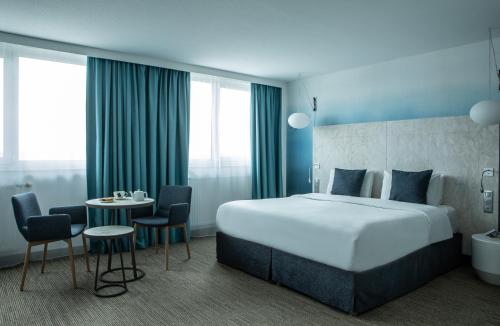 een hotelkamer met een bed en een tafel en stoelen bij Mercure Vannes Le Port in Vannes