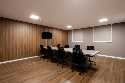 a conference room with a long table and black chairs at Slaviero Rondonópolis Centro in Rondonópolis