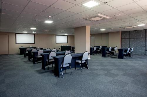 a conference room with tables and chairs and screens at Slaviero Rondonópolis Centro in Rondonópolis