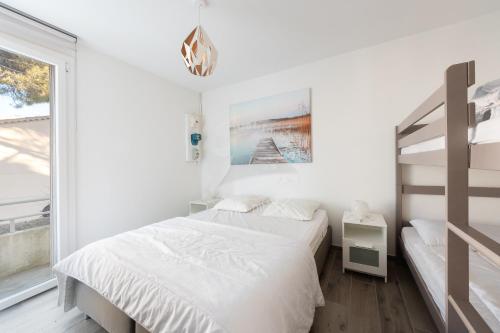 - une chambre blanche avec 2 lits et une fenêtre dans l'établissement AS15280 - P3 face à la mer avec garage privé à 2 pas du Centre Ville, au Grau-du-Roi